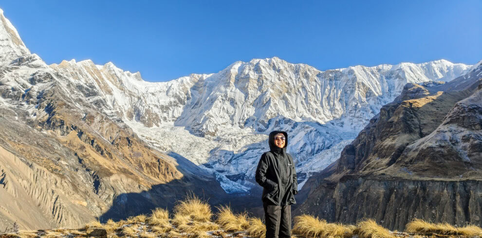 Breathtaking Himalayan mountain scenery with a smiling woman in outdoor gear.